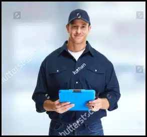 Man in dark blue uniform and cap holding a blue tablet, smiling at the camera, with a blurred background.