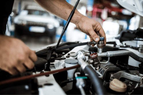 Auto air conditioning repair in Parkton, NC. with Brian's Motor Werkes. Image of mechanic hands fastening ac repair machine on car while testing the system.